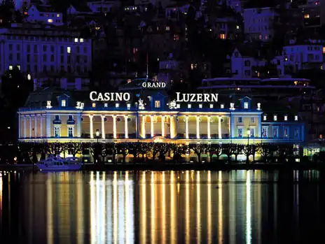 Façade illuminée du Grand Casino Luzern la nuit, au bord du lac des Quatre-Cantons